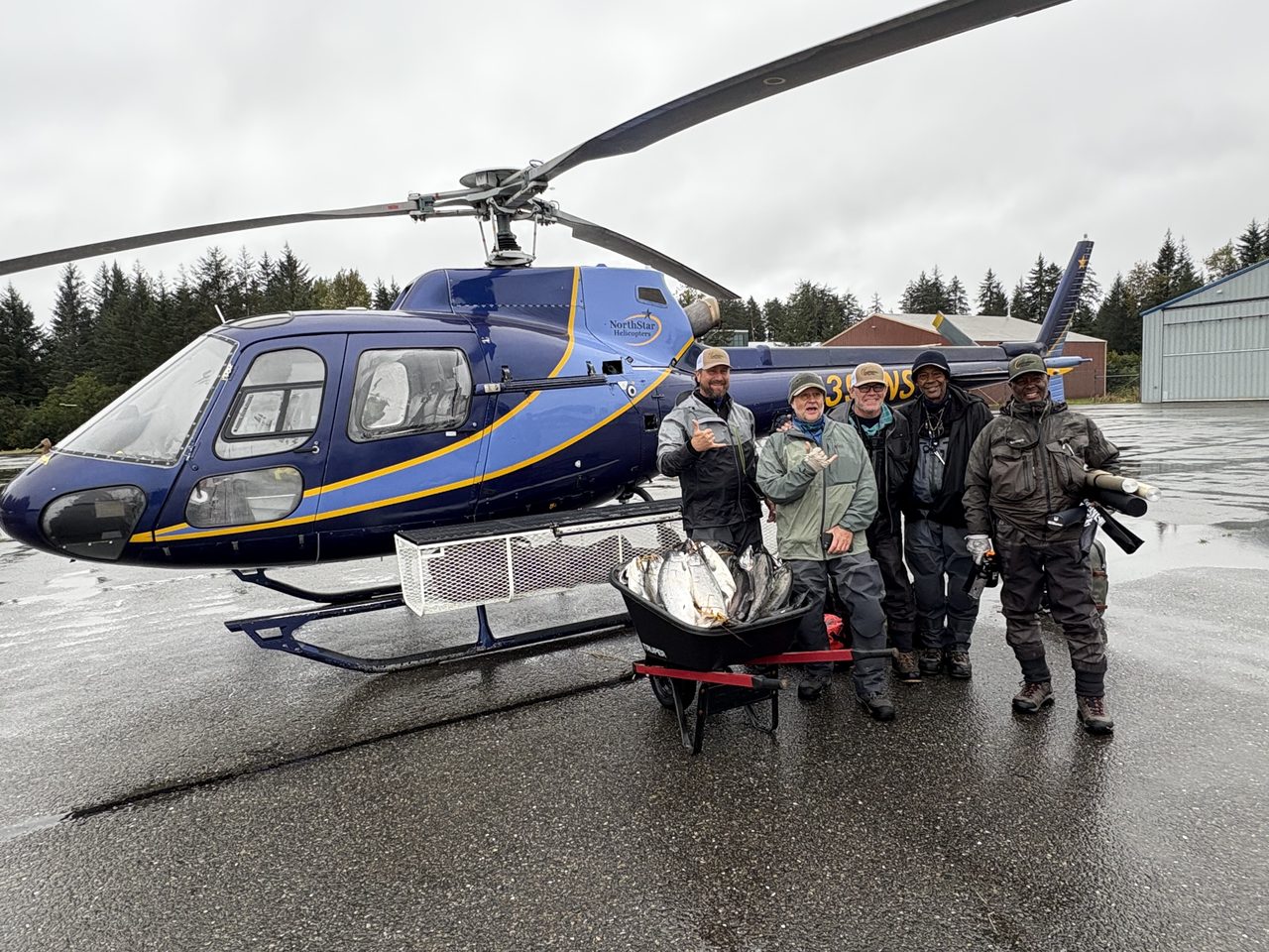 Two Yakutat Expeditions helicopters outside a hangar in morning fog.