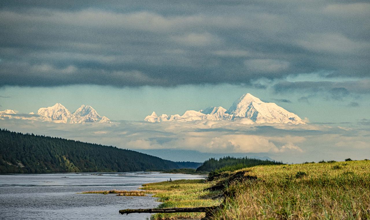 A wide Alaskan river with snow-capped peaks on the horizon.